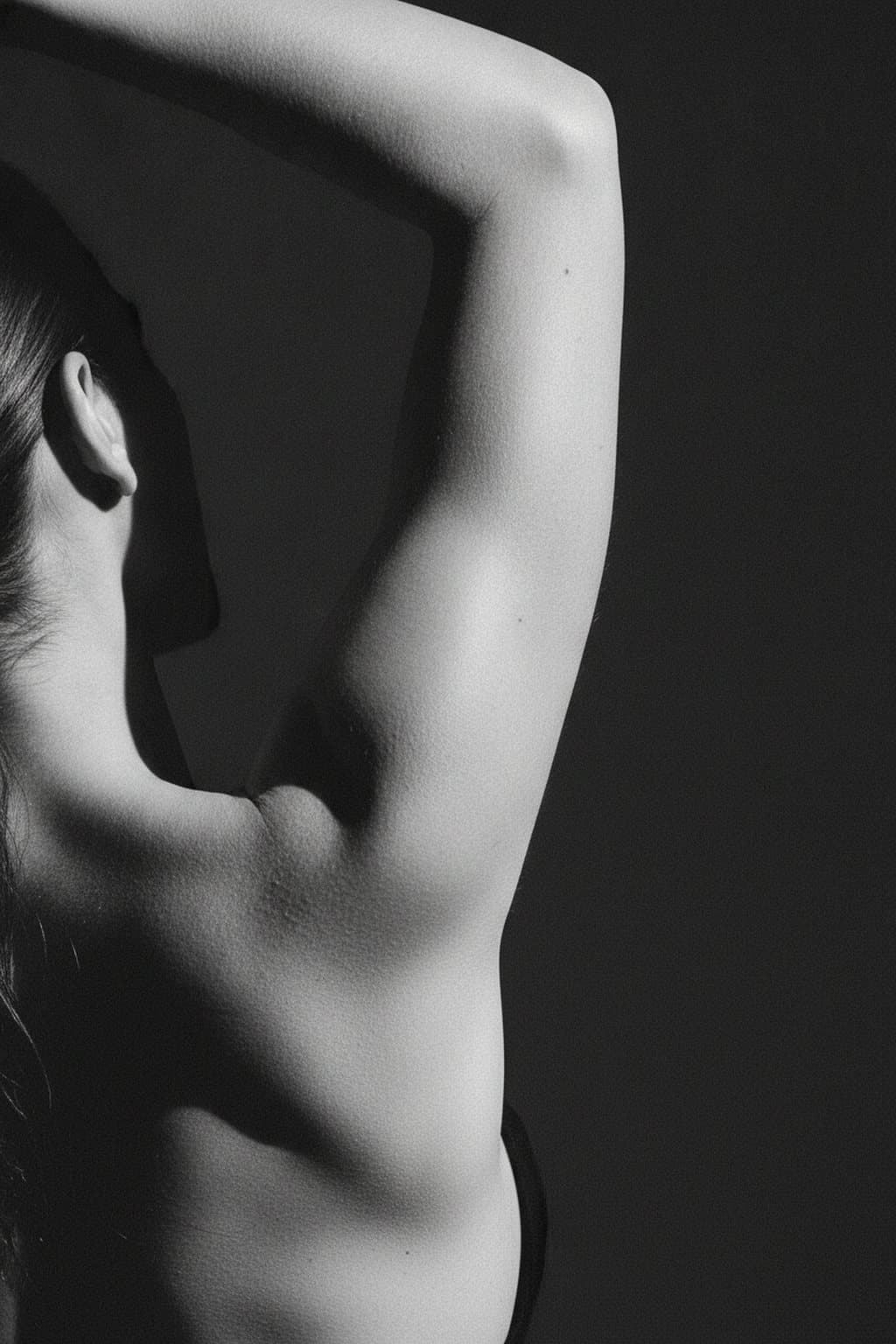 Black-and-white form study of a raised arm and shoulder line. Illustrative image — not a patient.