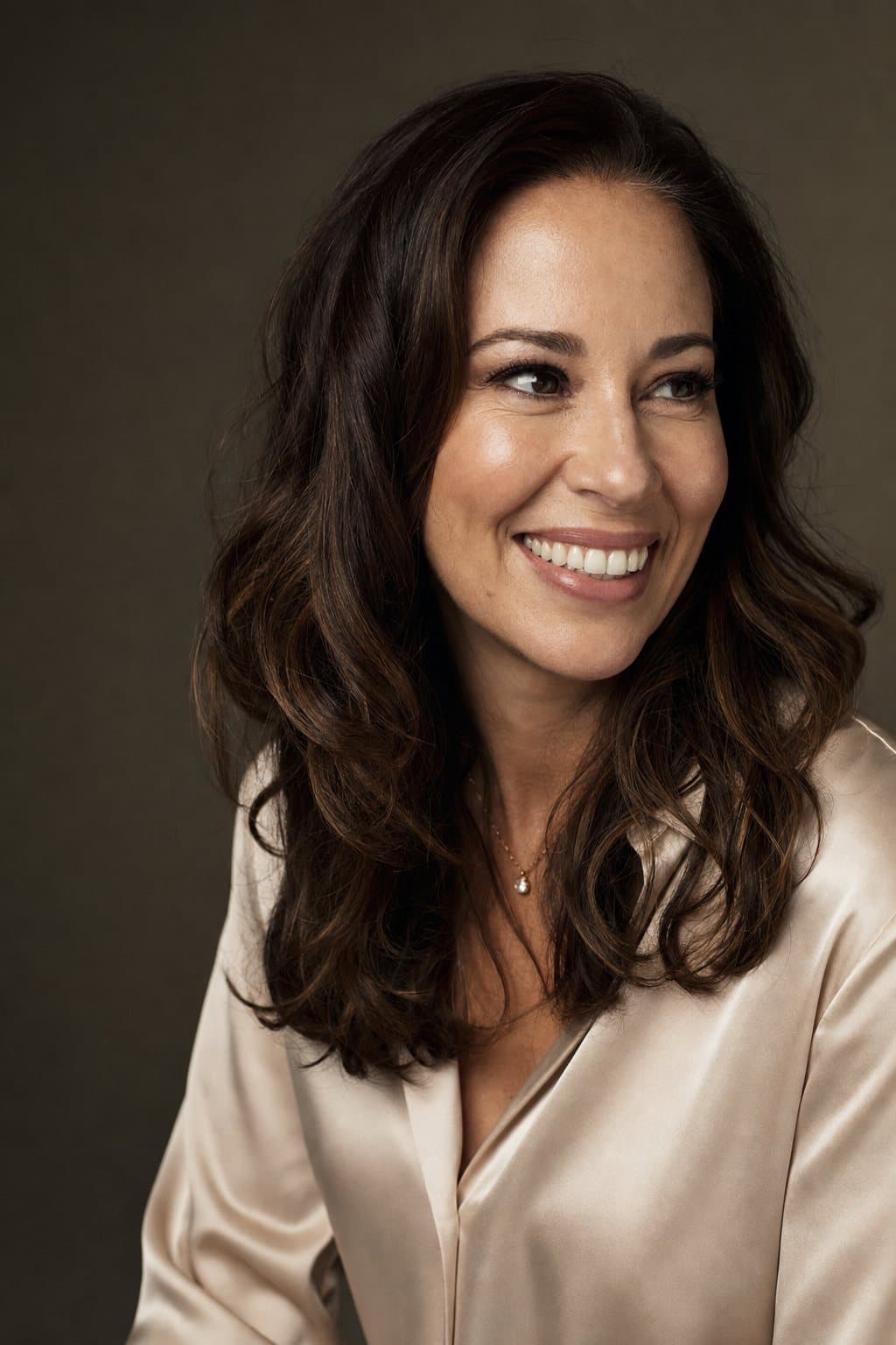 A polished woman in her late thirties in silk, a genuine warm smile. Illustrative image — not a patient.