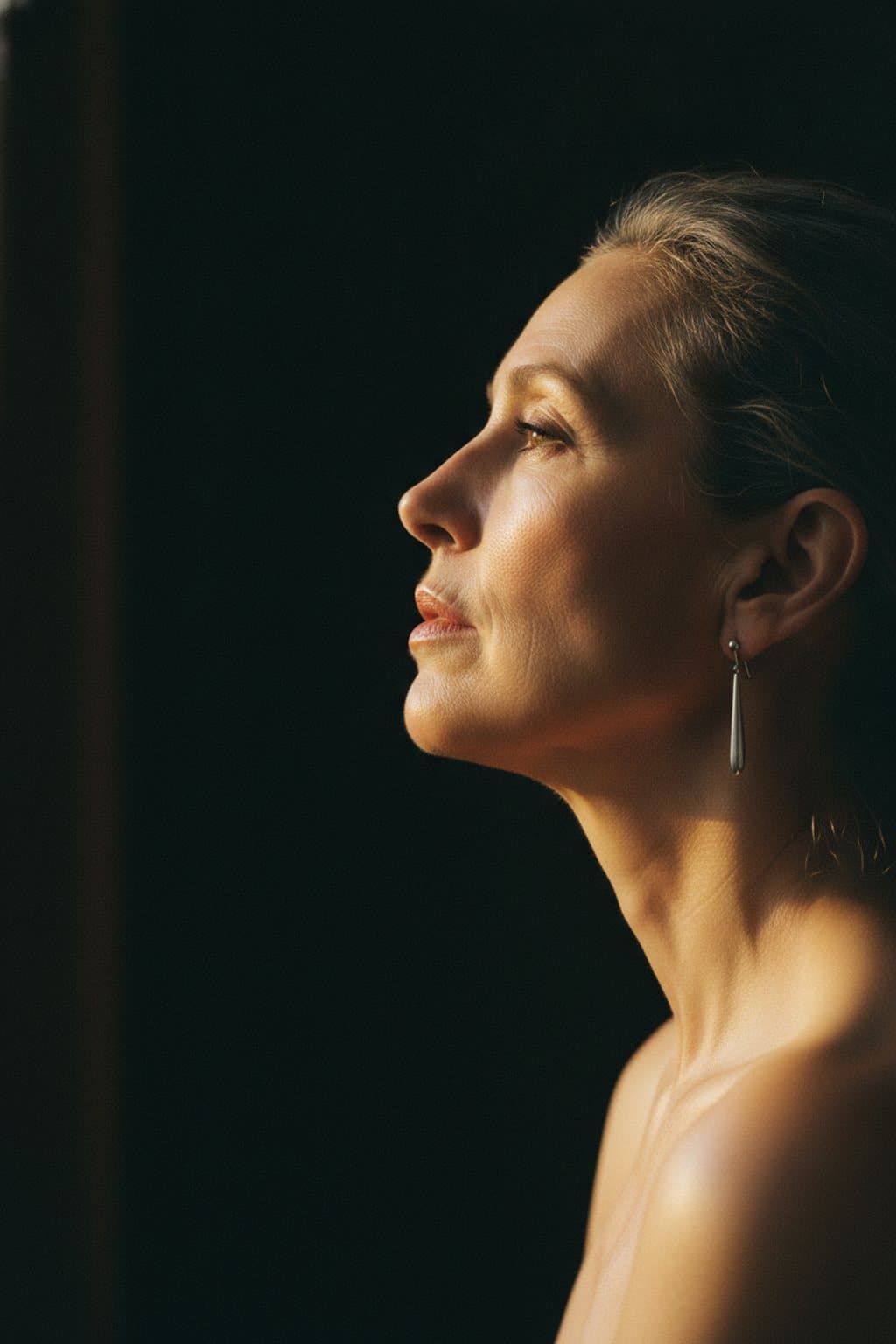Profile crop from lips to collarbone, light tracing the jaw and neck. Illustrative image — not a patient.