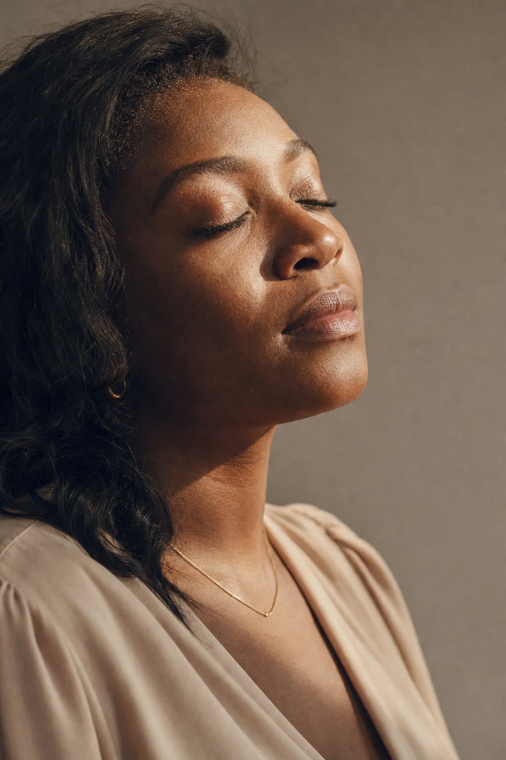 Eyes closed toward warm light, fresh luminous skin. Illustrative image — not a patient.