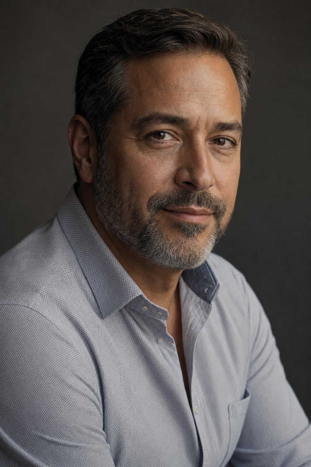 A well-groomed man in his late forties, confident easy half-smile, warm side light. Illustrative image — not a patient.