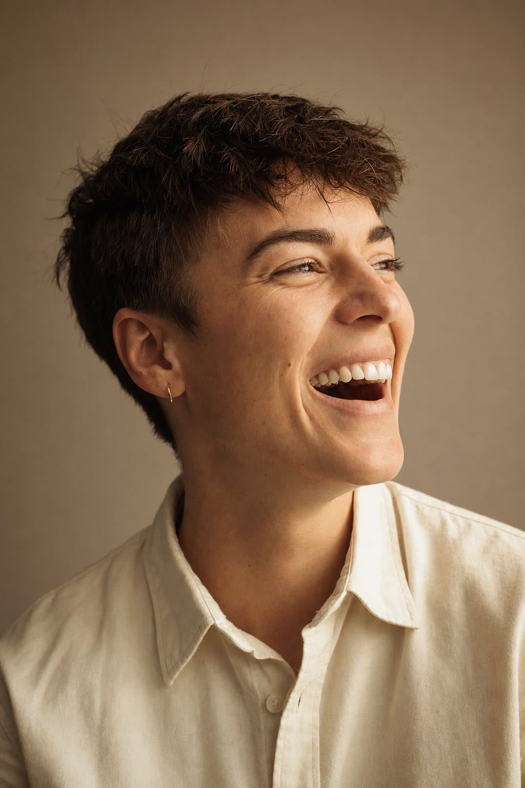 Warm portrait, easy authentic laugh, short styled hair. Illustrative image — not a patient.